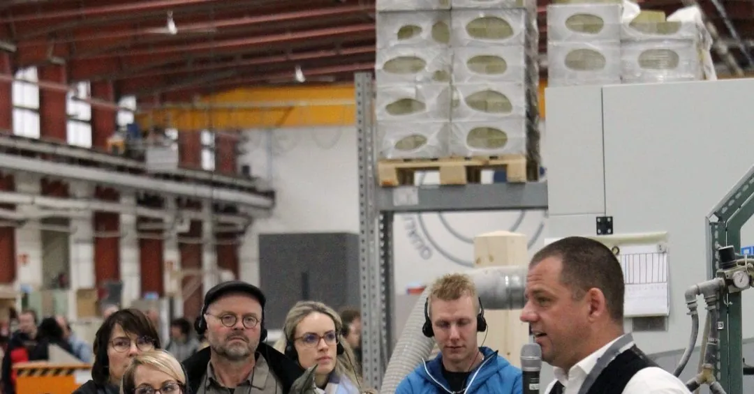 Ein Schwabenhaus-Mitarbeiter erklärt Besucherinnen und Besuchern mit Kopfhörern die Fertigung in der Manufaktur