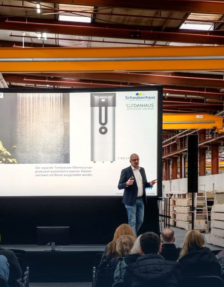Bauherren-Seminar zur Wärmepumpe vor großer Leinwand in der Werkshalle