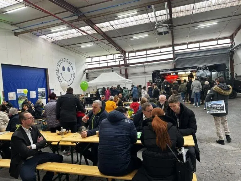 Gäste an Biertischen beim gemeinsamen Essen in der Halle
